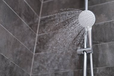 Banyodaki duş başlığından akan su damlaları yakın planda.
