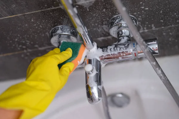 Háziasszony gumikesztyű mosás csap a fürdőszobában szivacs közelkép — Stock Fotó