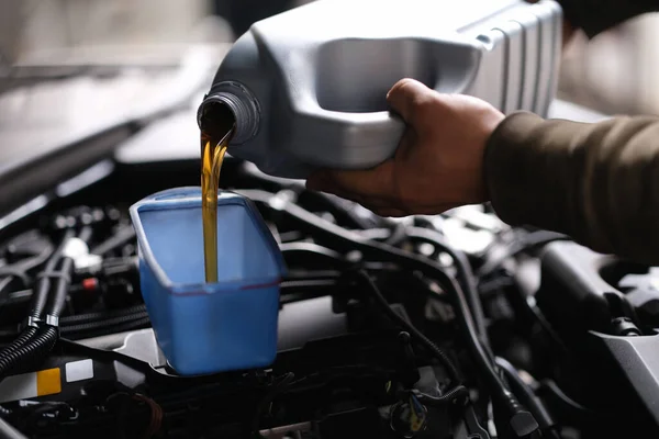 Maître réparateur versant l'huile moteur dans le gros plan moteur de la voiture — Photo