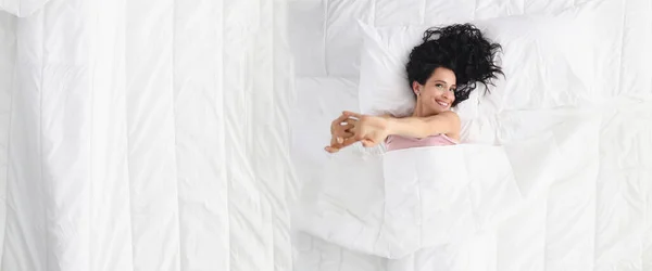 Hermosa joven sonriente mujer se encuentra en la cama grande con ropa de cama blanca pastel —  Fotos de Stock