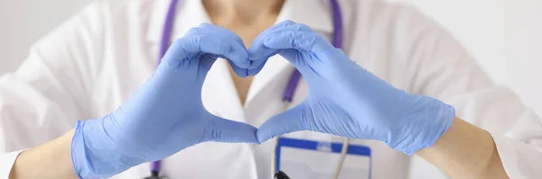 Врач в защитной медицинской маске показывает сердце руками — стоковое фото
