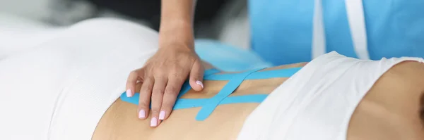 Médico corrige fita cinesio na coluna vertebral em paciente com dor nas costas. — Fotografia de Stock