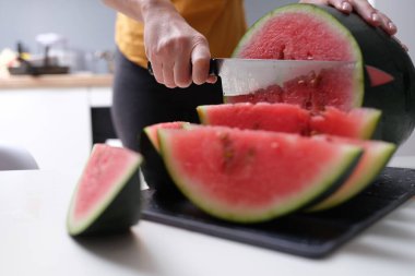 Evde karpuz kesen bir kadın var.