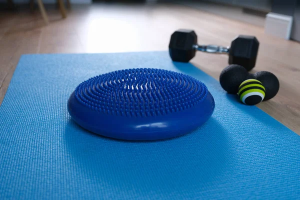 Cuscino di equilibrio blu sdraiato sul tappeto vicino ai manubri e roll ball home primo piano — Foto Stock