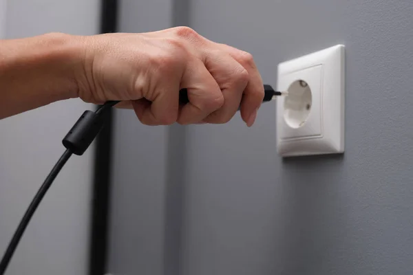 Woman hand inserts electrical plug into outlet closeup Stock Image