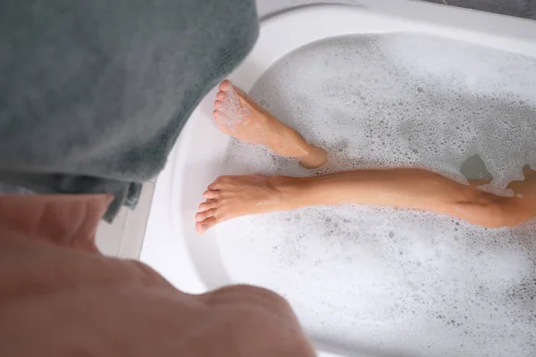 Female feet lying in water in bath closeup top view