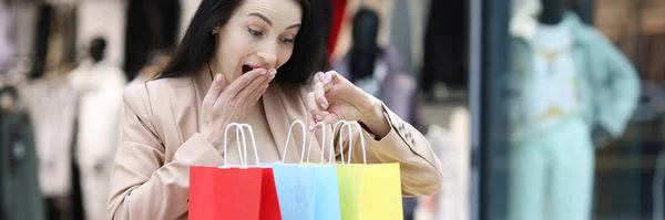 Begeisterte Frau blickt in Einkaufstüten in Einkaufszentrum — Stockfoto