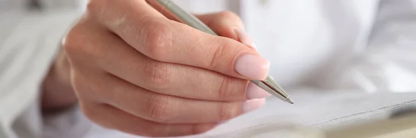 Woman doctor writes patient data into documents with pen