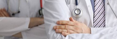 Boyunlarında steteskop olan doktorlar kollarını kavuşturup yakın plan çekiyorlar.