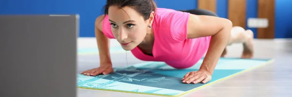 Femme en vêtements de sport debout dans la planche sur le sol en face de l'ordinateur portable — Photo