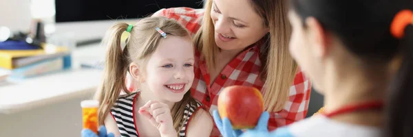 Pediatriker läkare som erbjuder mor och barn äpple eller burk med läkemedel — Stockfoto