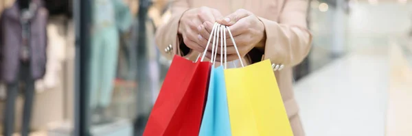 Kvinna som håller i händerna många flerfärgade papperspåsar med inköp i butik närbild — Stockfoto