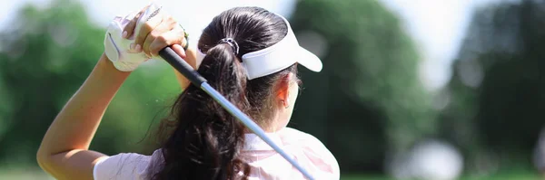 Female golfer stands with her back and holds golf club in her hands. — Stock Photo, Image