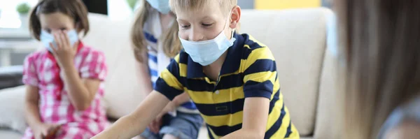 Crianças em máscaras de proteção médica jogar jogos de tabuleiro em casa. — Fotografia de Stock