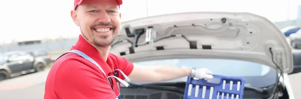 Портрет молодого усміхненого ремонтанта автомобіля з набором інструментів на капоті автомобіля — стокове фото
