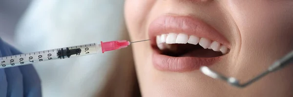 입을 벌리고 치과 의자에 앉아 마취 주사를 맞고 있는 젊은 여성 환자의 모습 — 스톡 사진