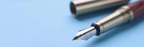 Open fountain pen on light blue background