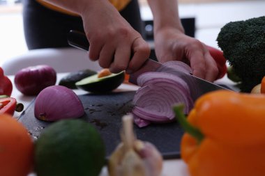 Kadın kırmızı soğanı yakın plan takozlara kesiyor.