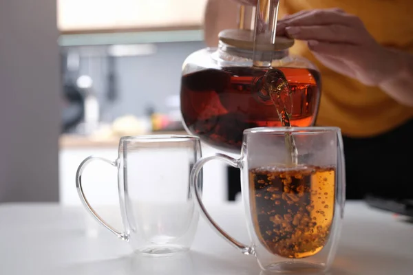 Frau gießt Tee aus gläserner Teekanne in Tasse ein — Stockfoto