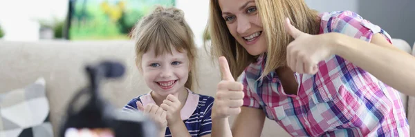 Kadın ve küçük kız evde kameranın önünde baş parmağını gösteriyorlar. — Stok fotoğraf