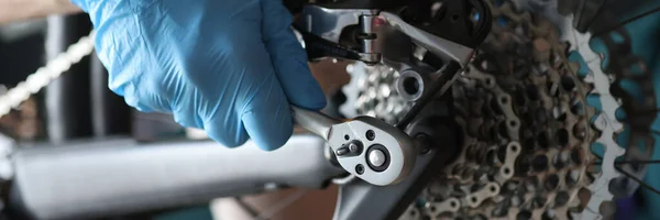 Handschoen klusjesman reparatie fietsketting met gereedschap close-up — Stockfoto
