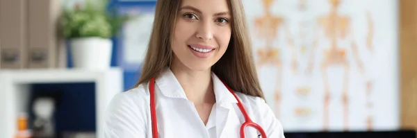 Молодая женщина-врач в форме с красным стетоскопом в клинике — стоковое фото
