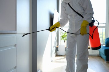Koruyucu tulumlu ve eldivenli işçiler apartmanı dezenfekte ediyor.