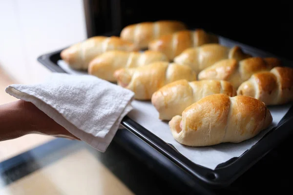 Ama de casa tomando caliente deliciosa boca riego bollos fuera del horno en la bandeja de hornear primer plano —  Fotos de Stock