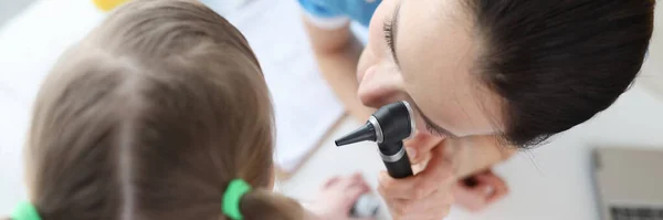 Otolaryngologist looks at little girl ear with otoscope closeup — Stock Photo, Image