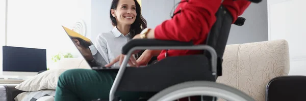 Donna in sedia a rotelle con computer portatile comunica con un amico — Foto Stock