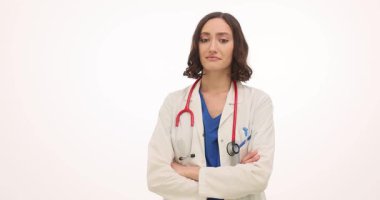 Yüzünde kafa karışıklığı olan steteskoplu kadın doktor beyaz arka planda duruyor. Kadın doktor yavaş çekim şüphesiyle aşağı ve yana bakıyor