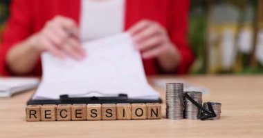 Sıcak bir ortamda, bir kişi madeni para biriktirirken önemli mali belgeleri inceler, ekonomik durgunluğun kişisel finans yönetimi üzerindeki etkisini vurgular.