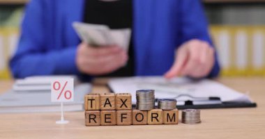 Bir kişi para sayar ve vergi reformunu tartışırken madeni para organize eder. Barışçıl ortam, vergilerin mali ve tasarrufları nasıl etkilediğine dair düşünceli bir değerlendirmeyi teşvik ediyor..