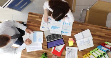 Genç kadın ve erkek ofis çalışanları masa başında oturup grafikli dokümanları incelerler. Çalışanlar tebrik yumruğu yumruklaşması yapar. Yavaş çekim