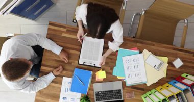 İş adamı önemli bir sözleşme belgesini müdüre teslim eder ve imza çizgisine doğru hareketler yapar. İş kadını belgeyi inceledi ve sayfaları imzaladı