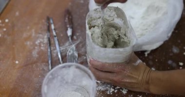 Kadın sıvayı ve suyu karıştırarak kremsi ve hatta kabın içindeki dokuyu oluşturur. Kadın, duvar sanatı yavaş çekim için ideal tutarlılık yaratır.