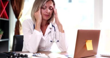 Hastanede dizüstü bilgisayar başında oturan yorgun kadın doktor masajları. Kadın hekim vardiyadan sonra klinikte fazla çalışmaktan yoruldu.