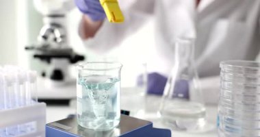 Kadın bilim adamı masadaki dijital sayaçla manyetik karıştırıcıdaki sıvı pH 'ı kontrol ediyor. Kadın kimyager, su örneğini laboratuarda modern aletlerle test ediyor.