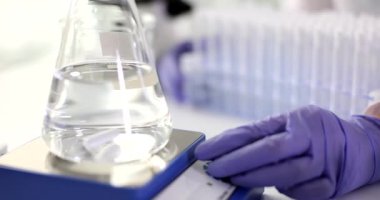 Yardımcı el, laboratuvarda dönen manyetik karıştırıcının kolunu çeviriyor. Eldivenli teknisyen, suyu laboratuvarda modern karıştırma cihazıyla test ediyor.