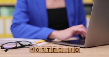 Bir insan, yanında renkli malzemeler ve bardaklarla çevrili güzel bir portföy hazırlarken dizüstü bilgisayarda yazar. Parlak çalışma alanı yaratıcılığa ilham verir..