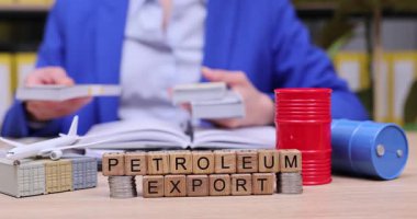 Hareketli bir çalışma alanında, odaklanmış bir birey modellerle etkileşim halinde iken belgeleri inceler ve petrol ihracatını engeller. Bu, petrol ticaretinin önemini vurguluyor.