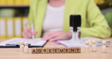 Canlı yeşil ceketli bir kişi önemli bir anlaşma imzaladı. Kağıtlar masanın üzerine düzgünce yerleştirilmiş, hem odaklanma hem de profesyonellik sergileniyor..