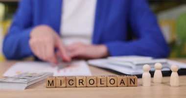 Kentsel bir ofiste, bir profesyonel mikro sonlanma seçeneklerini tartışırken kağıtlara yazı yazar. Küçük rakamlar, girişimleri için mali destek arayan müşterileri temsil ediyor.