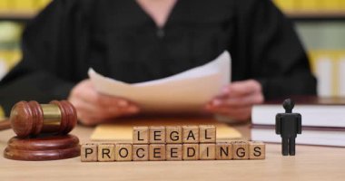 Yargıç, kitap ve yasal eşyalarla dolu bir masada otururken önemli belgeleri inceler. Mahkeme salonunda yasal süreç ilerledikçe ortamın durumu ciddileşiyor..