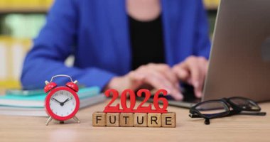 Kendini işine adamış bir birey, başarı araçlarıyla çevrili olan dizüstü bilgisayarına dikkatle odaklanır. Saat 2026 'yı gösteriyor, önümüzde uzanan her şey için umut ve hırs besliyor..