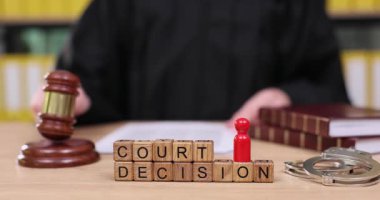 Bir yargıç önemli bir mahkeme kararını açıklamaya hazırlanırken önemli belgeleri gözden geçirir. Bu an, mahkeme salonundaki hukuki sürecin ciddiyetini ve ciddiyetini yansıtıyor..