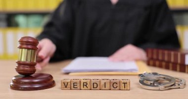 Yoğun bir mahkeme salonunda yargıç önemli bir kararı açıklamak için tokmağı kaldırır. Evraklar karıştırılmış ve yasal belgeler davaya atıfta bulunuyor. Gerginlik, adaletin yerini bulması için havayı dolduruyor..