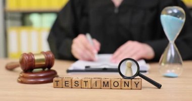 Odaklanmış bir ortamda, siyah giyinmiş bir birey hayati bir ifade yazar. Beklenti ve umutla dolu sessiz bir mahkeme salonundaki aciliyeti simgeleyen bir kum saati iniyor..