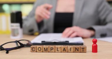 Hareketli bir ofiste, odaklanmış bir birey bir belgeyi inceler, bir şikayeti damgalar ve endişeleri gidermeye hazırlanır. Net iletişim ve çözünürlüğe odaklan.