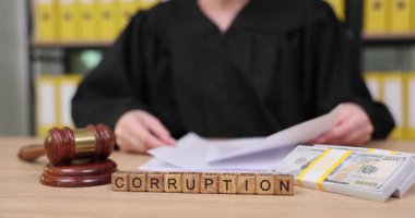 Bir mahkeme salonunda, bir yargıç belgeleri incelerken, bir tokmak ve yığınla para yolsuzluğu simgeliyor. Ciddi atmosfer adaletin gerginliğini yansıtıyor..